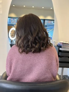 Femme souriante dans un salon de coiffure à Lille, avec une coloration ton sur ton brillante et naturelle réalisée sans ammoniaque.