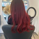 Femme aux cheveux rouges éclatants avec coupe moderne, reflet cuivré lumineux et coloration professionnelle, style tendance et entretien optimal des cheveux rouges.