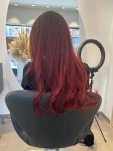 Femme aux cheveux rouges éclatants avec coupe moderne, reflet cuivré lumineux et coloration professionnelle, style tendance et entretien optimal des cheveux rouges.