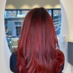 Femme aux cheveux roux flamboyants avec mèches naturelles et effet éclatant.