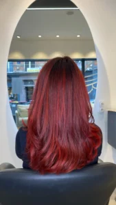 Femme aux cheveux roux flamboyants avec mèches naturelles et effet éclatant.
