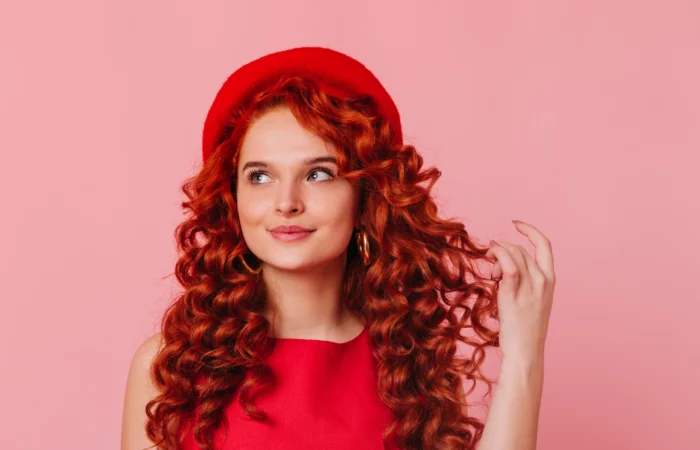 Cheveux rouges éclatants avec nuances cuivrées et rouges profonds, coupe stylée et brillante, coloration professionnelle longue tenue, tendance capillaire moderne pour un look audacieux et élégant.
