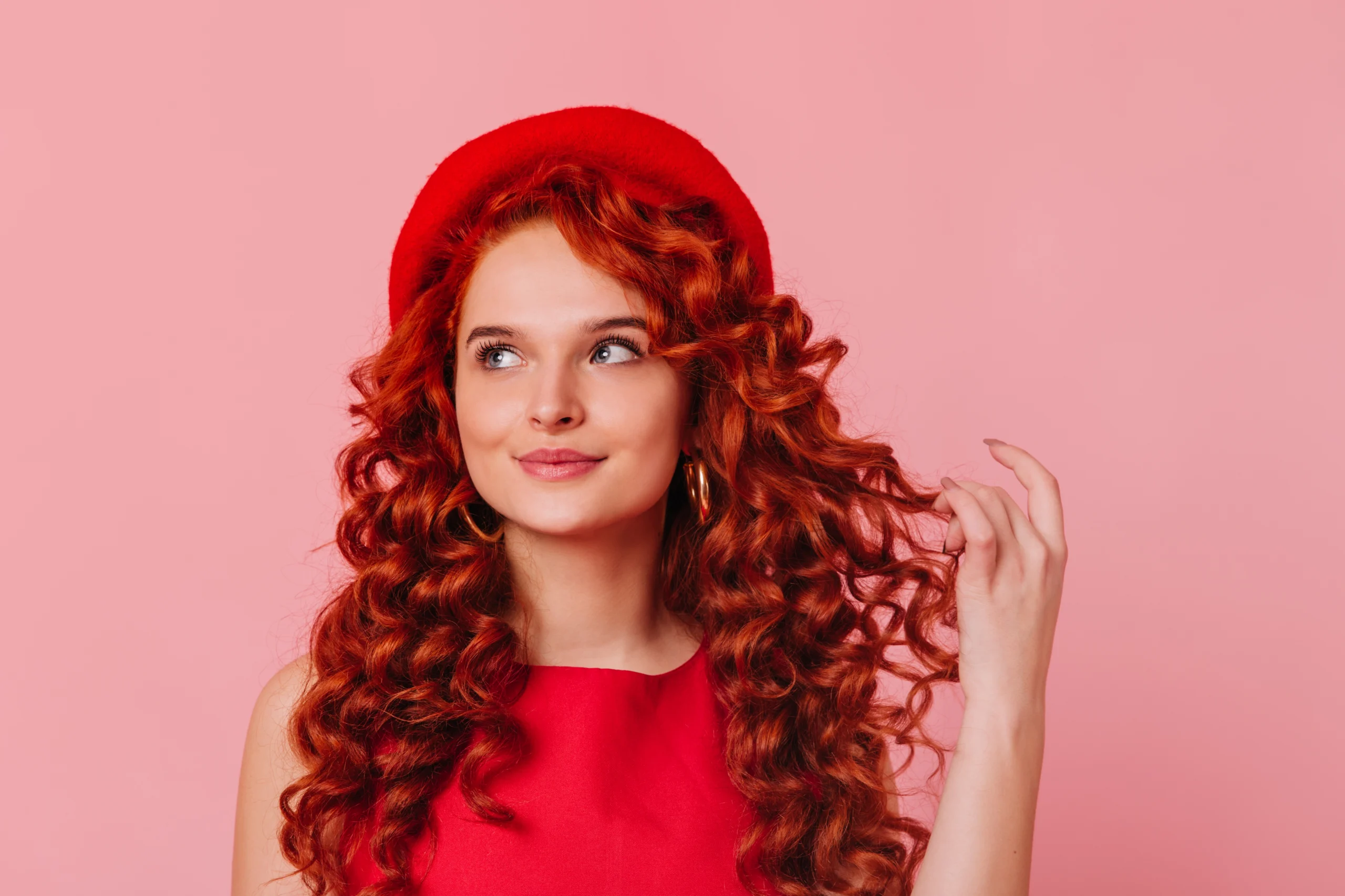 Cheveux rouges éclatants avec nuances cuivrées et rouges profonds, coupe stylée et brillante, coloration professionnelle longue tenue, tendance capillaire moderne pour un look audacieux et élégant.