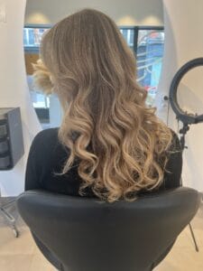Cheveux longs avec balayage blond chaud et ondulations naturelles, réalisés par les coloristes experts de La Maison du Coloriste à Lille.
