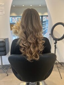 Balayage blond lumineux sur cheveux longs ondulés réalisé à La Maison du Coloriste, salon de coiffure spécialiste du balayage à Lille.