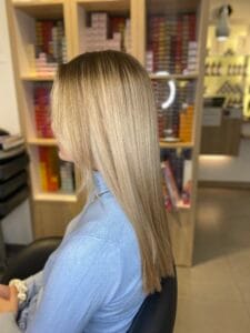 Cheveux longs lissés avec balayage miel et racines naturelles