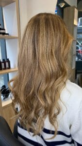 Cheveux longs bouclés avec balayage miel, reflets dorés en mouvement