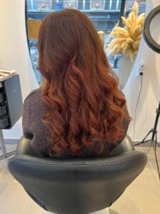 Cheveux longs cuivrés bouclés, reflets chauds et lumineux réalisés au salon La Maison du Coloriste Lille