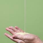 Femme souriante appliquant un shampoing clean beauty, routine capillaire naturelle et plaisir sensoriel.