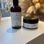 Ingrédients capillaires naturels vegan : huile végétale, avocat, menthe, romarin, graines, beurre de karité et flacons de soins.