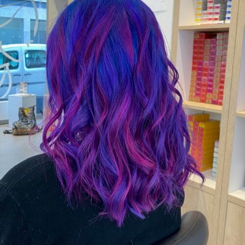 Coloration violette à Lille : cheveux bleu-violet avec mèches fuchsia – réalisation salon de coiffure lille