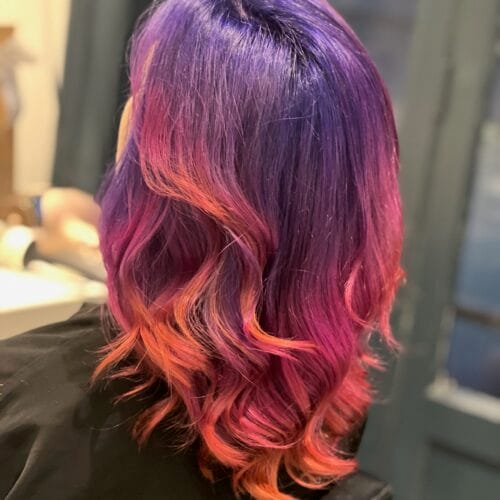 Coloration créative à Lille : cheveux violet profond avec reflets rose et pointes cuivrées