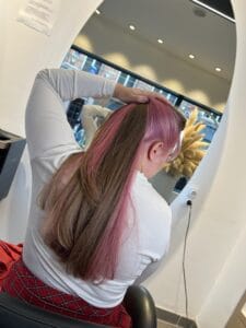Underlight rose cheveux à la nuque, mèches colorées visibles sur un chignon