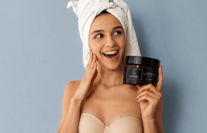 Coiffeur Lille – Masque Chroma Protect La Maison du Coloriste tenu par une femme après sa routine beauté. Ce masque professionnel pour cheveux colorés nourrit intensément la fibre capillaire, protège durablement la couleur, préserve la brillance et apporte douceur et réparation. Disponible chez votre coloriste expert à Lille, Place Rihour, spécialiste de la coloration, du balayage et des soins capillaires professionnels.