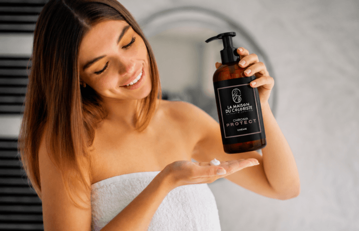 Coiffeur Lille – Femme appliquant la Crème Chroma Protect La Maison du Coloriste après sa routine capillaire. Ce soin sans rinçage professionnel protège les cheveux colorés, hydrate intensément la fibre, préserve l'éclat de la coloration, réduit les frisottis et apporte douceur et brillance. Disponible chez votre coloriste expert à Lille, Place Rihour, spécialiste de la coloration, du balayage et des soins capillaires.
