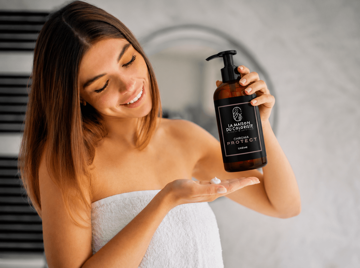 Coiffeur Lille – Femme appliquant la Crème Chroma Protect La Maison du Coloriste après sa routine capillaire. Ce soin sans rinçage professionnel protège les cheveux colorés, hydrate intensément la fibre, préserve l'éclat de la coloration, réduit les frisottis et apporte douceur et brillance. Disponible chez votre coloriste expert à Lille, Place Rihour, spécialiste de la coloration, du balayage et des soins capillaires.